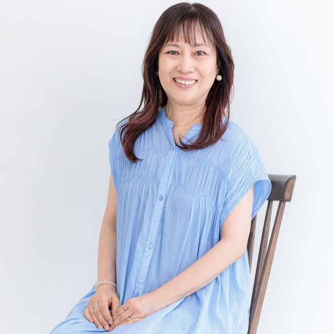 レッスン室のピアノのそばで先生が子どもに目線を合わせ、楽譜を開いて話している様子